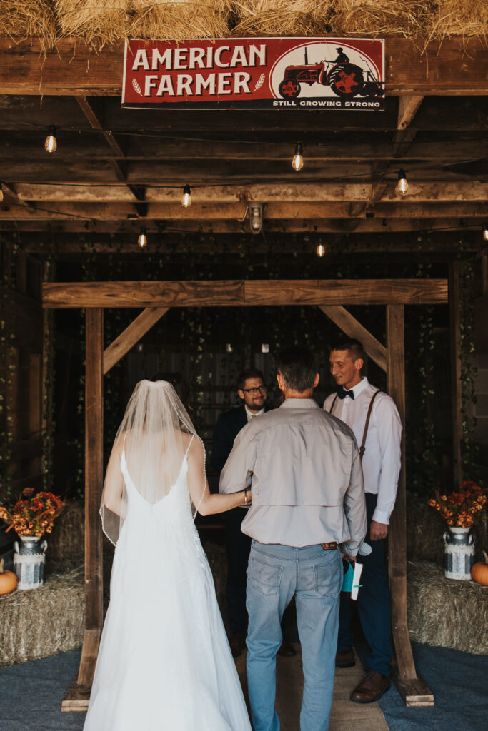 bride walking down the aisle of the barn with her father