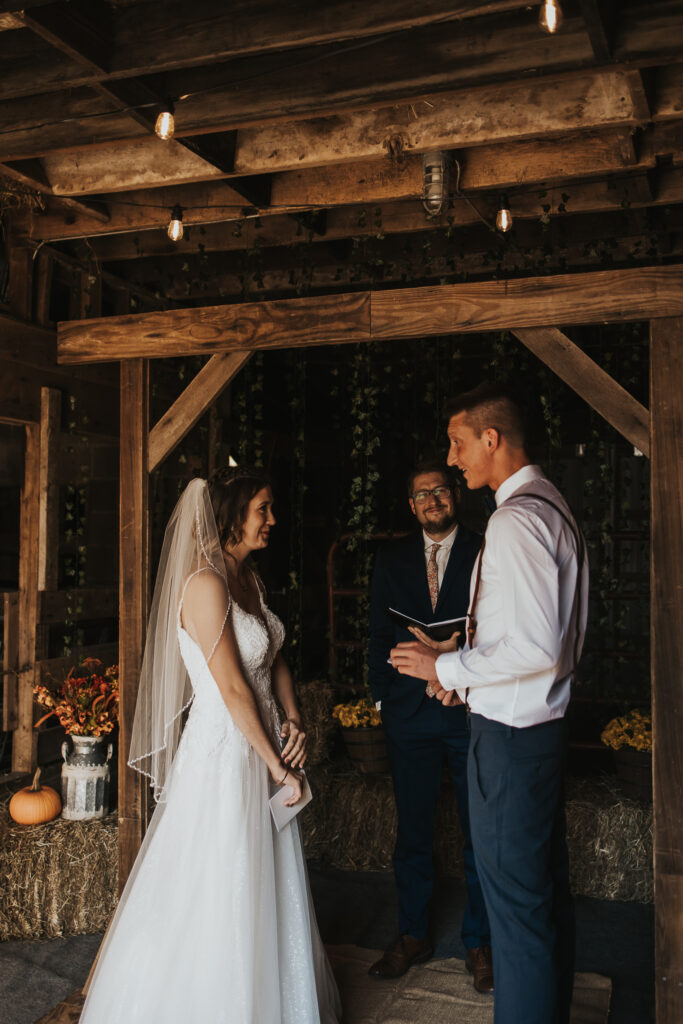 couple exchange vows during ceremony in the barn of their intimate backyard wedding