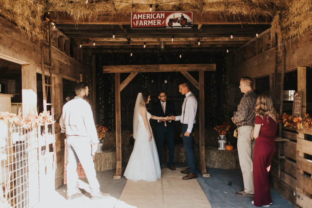 couple hold hands during ceremony of intimate backyard wedding