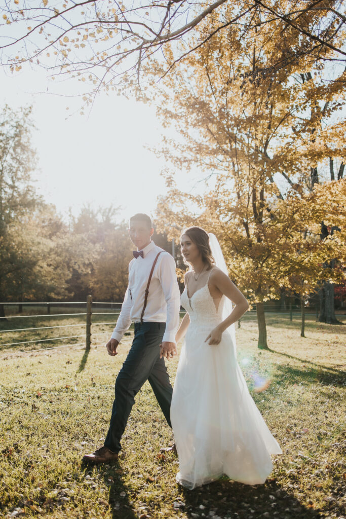 couple walks holding hands in the pasture after their intimate backyard wedding
