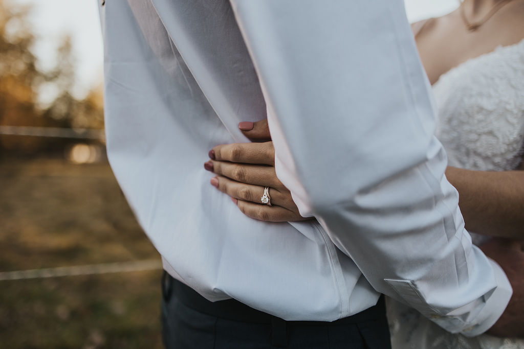 couple embrace showing off wedding ring
