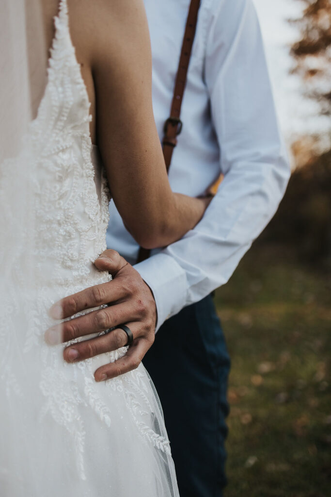 couple embrace showing off wedding ring