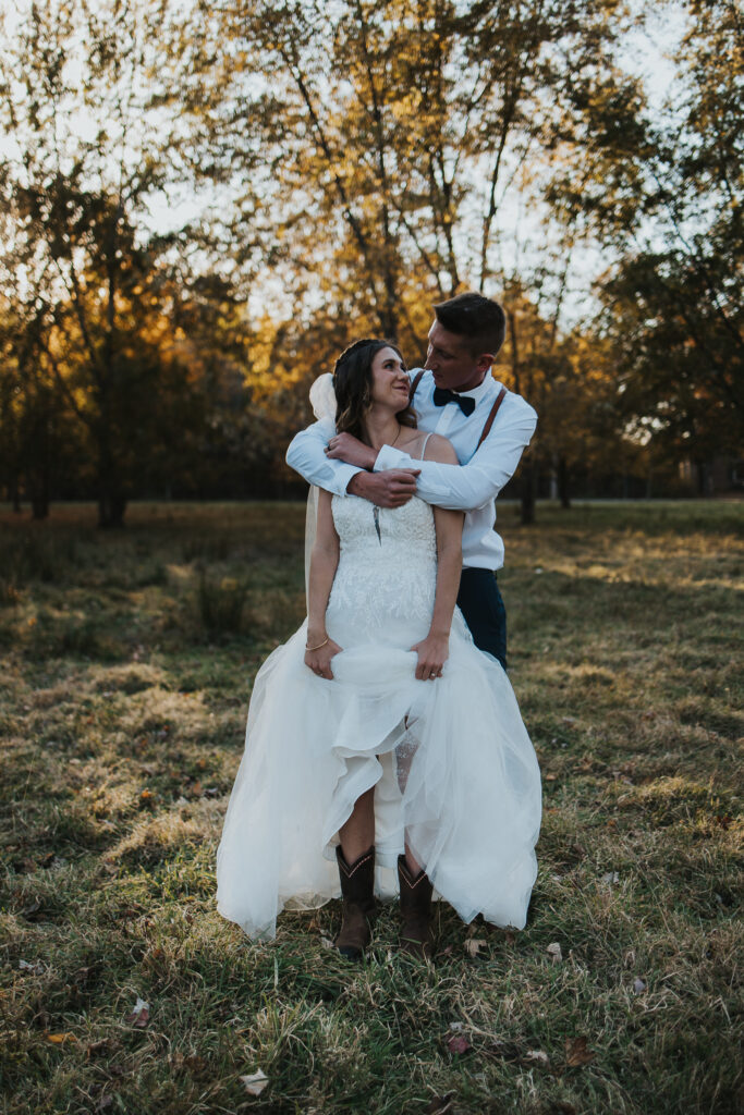 couple embrace while bride shows off cowboy boots