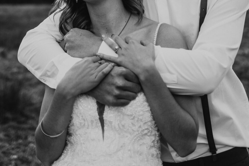 couple embrace showing off wedding ring