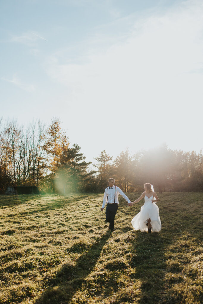 couple walks holding hands in the pasture after their intimate backyard wedding