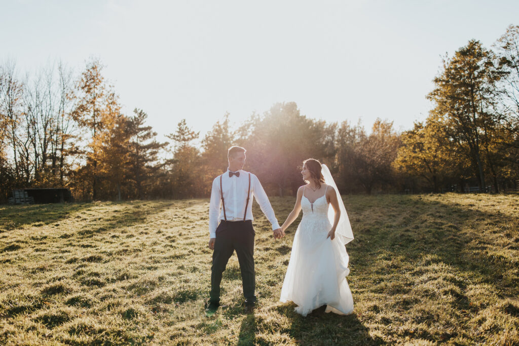 couple walks holding hands in the pasture after their intimate backyard wedding