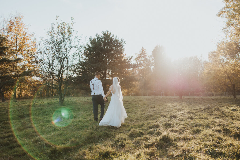 couple walks holding hands in the pasture after their intimate backyard wedding