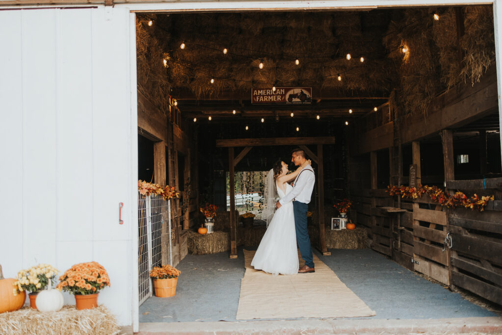couple embrace in the barn of their intimate backyard wedding