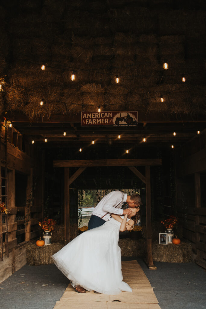couple kiss in the barn of their intimate backyard wedding