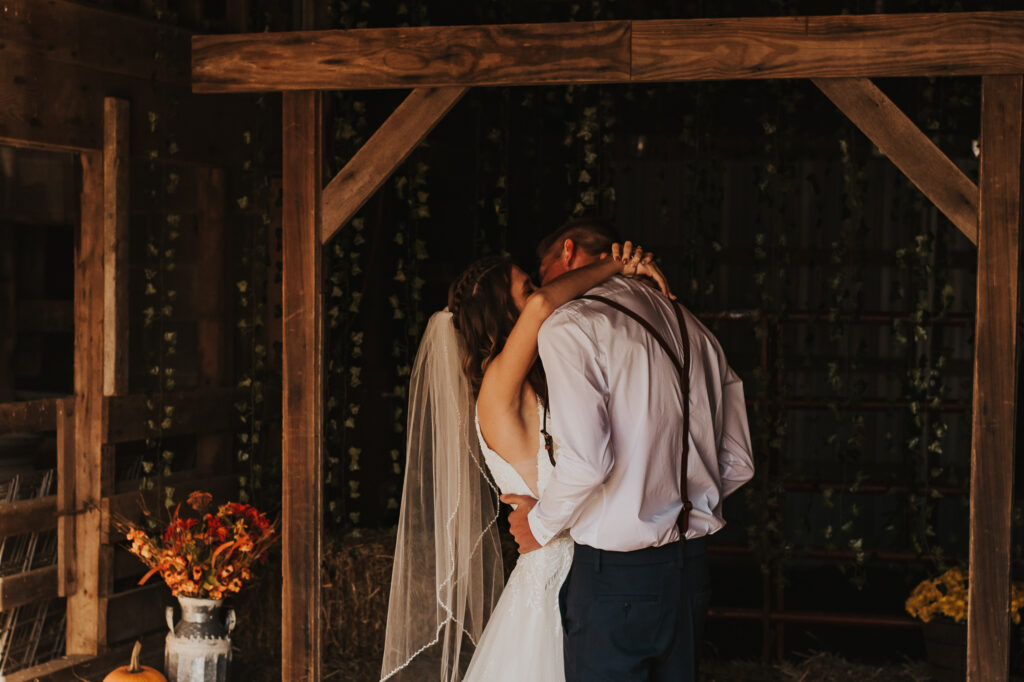 couple kiss during ceremony of their intimate backyard wedding
