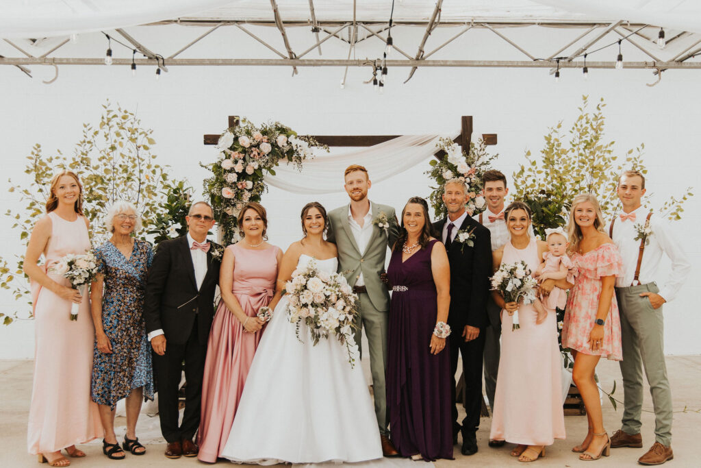 couple poses with family on wedding date