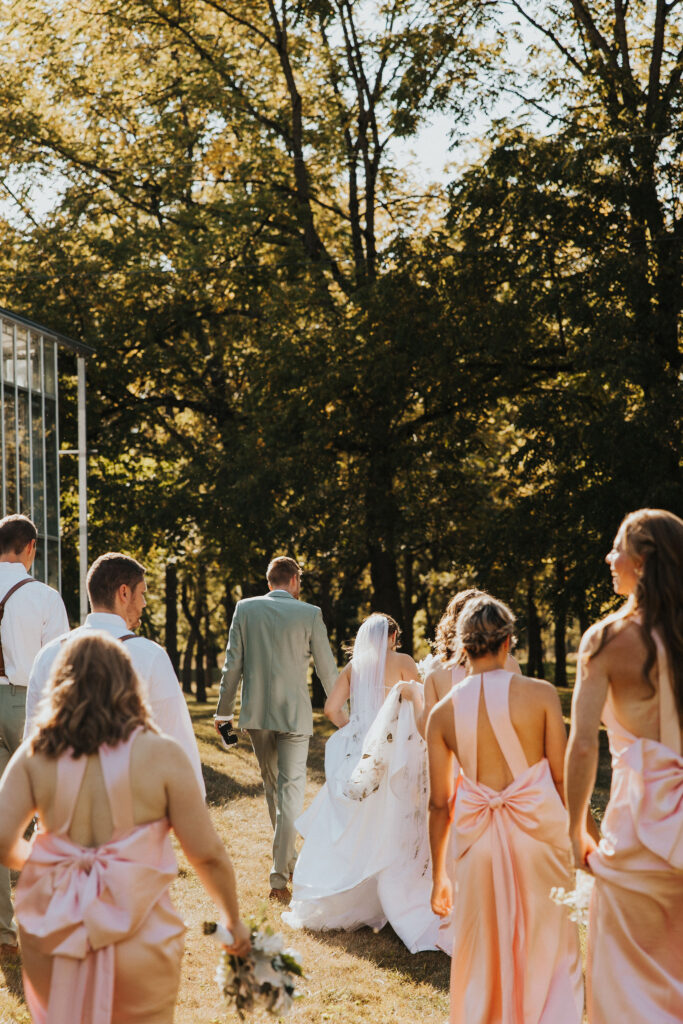 couple walks with wedding party at outdoor wedding 