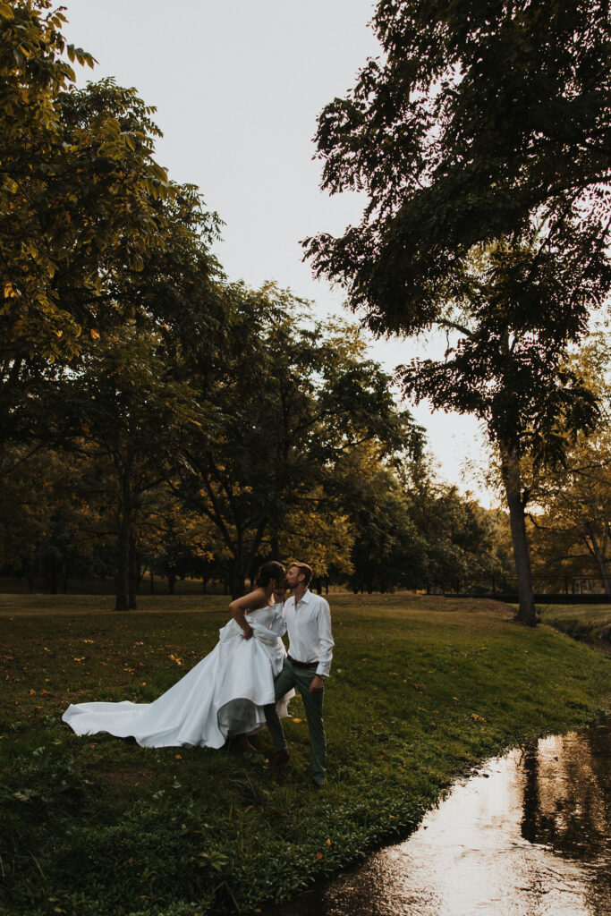 couple kisses by river at outdoor Ohio wedding venue