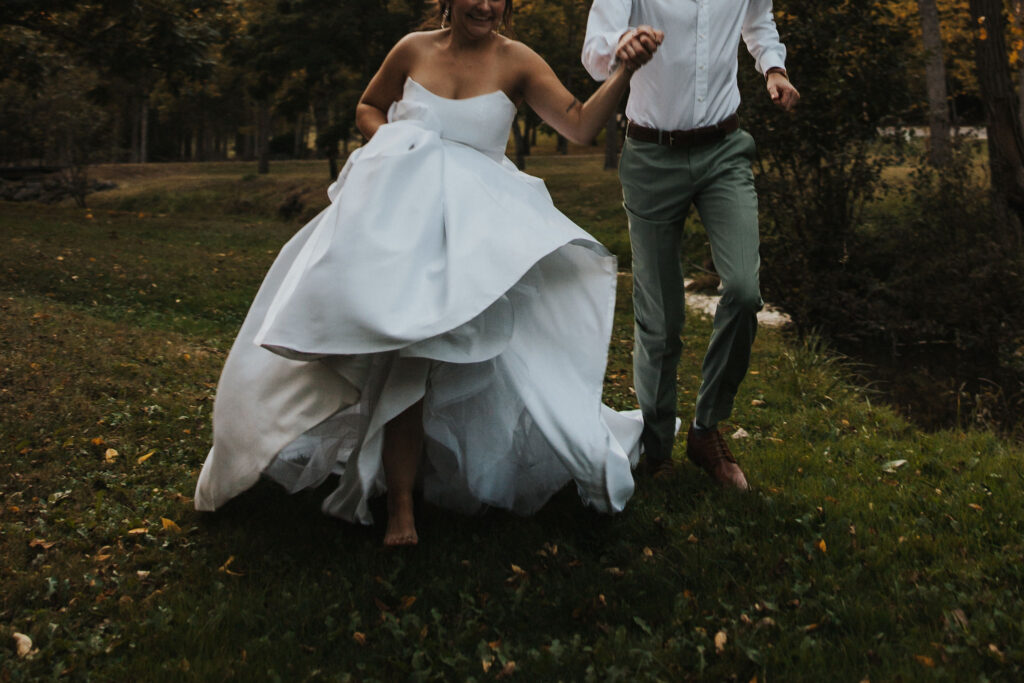 couple runs through field during wedding sunset photos