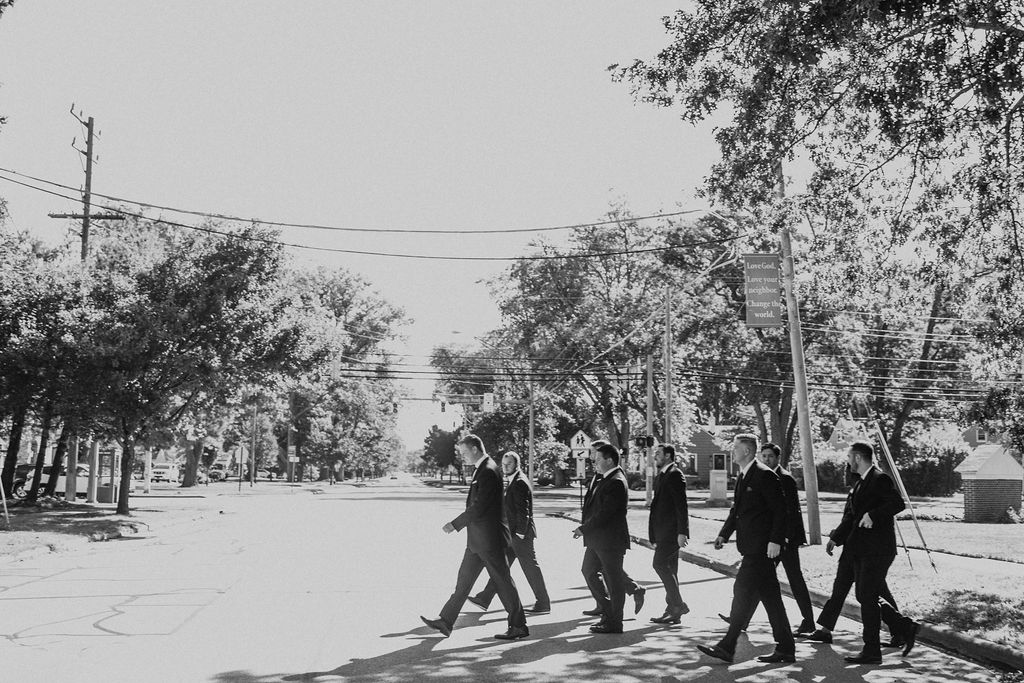 groom walks across street with groomsmen