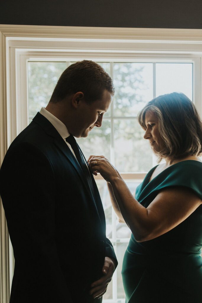 groom gets ready with mother of the bride