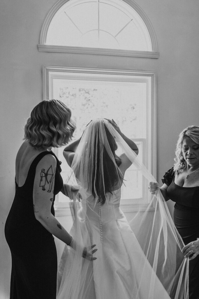 bride has help putting on wedding veil