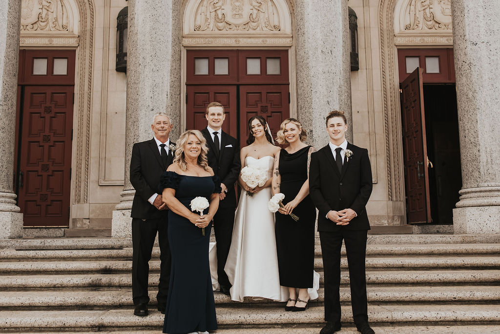 couple poses with family on church steps