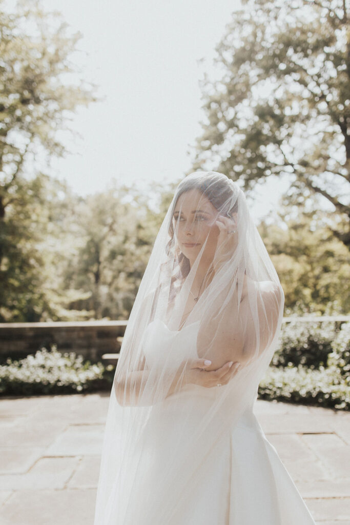 bride poses under white wedding veil