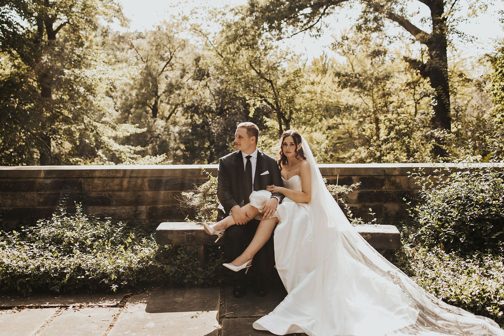 bride sits on groom's lap at outdoor garden