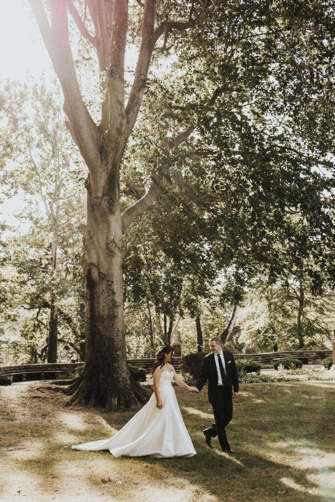 couple walks holding hands during wedding first look in Cleveland Cultural Gardens