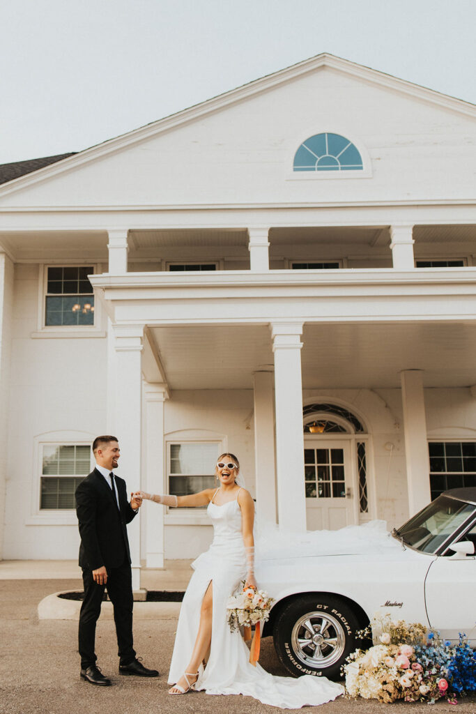 couple holds hands posing on white car