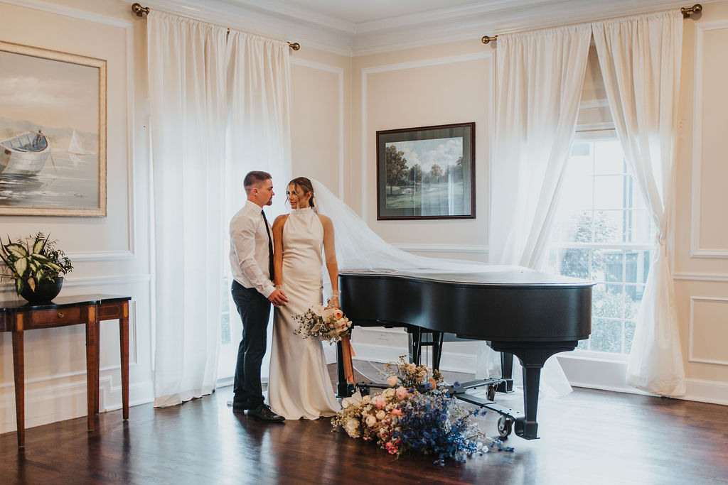 couple poses by florals and piano at Ohio wedding venue 