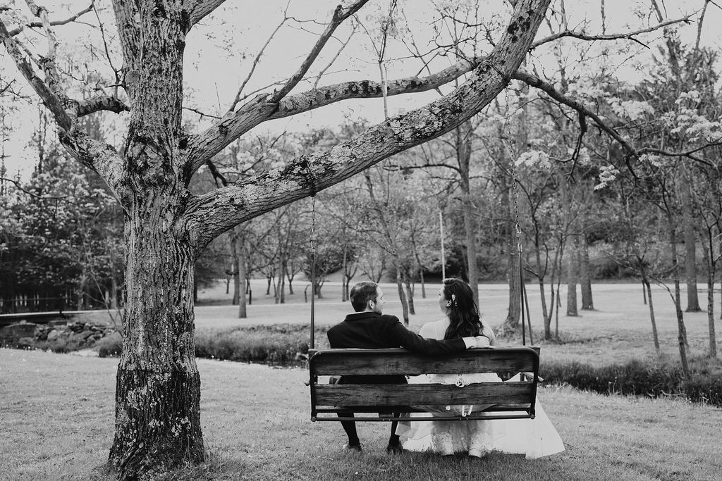 couple sits on bench at outdoor wedding