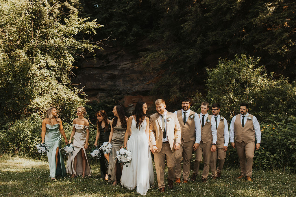 couple walks with wedding party in forest