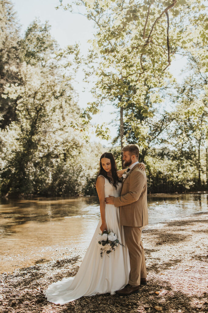 couple embraces besides river