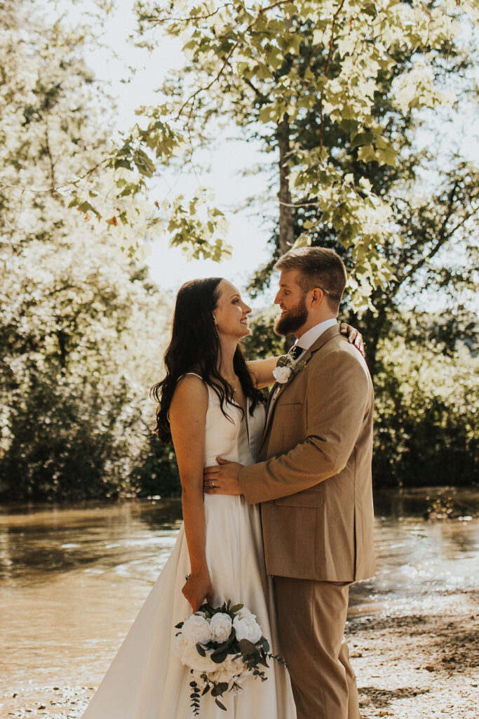 couple embraces beside river