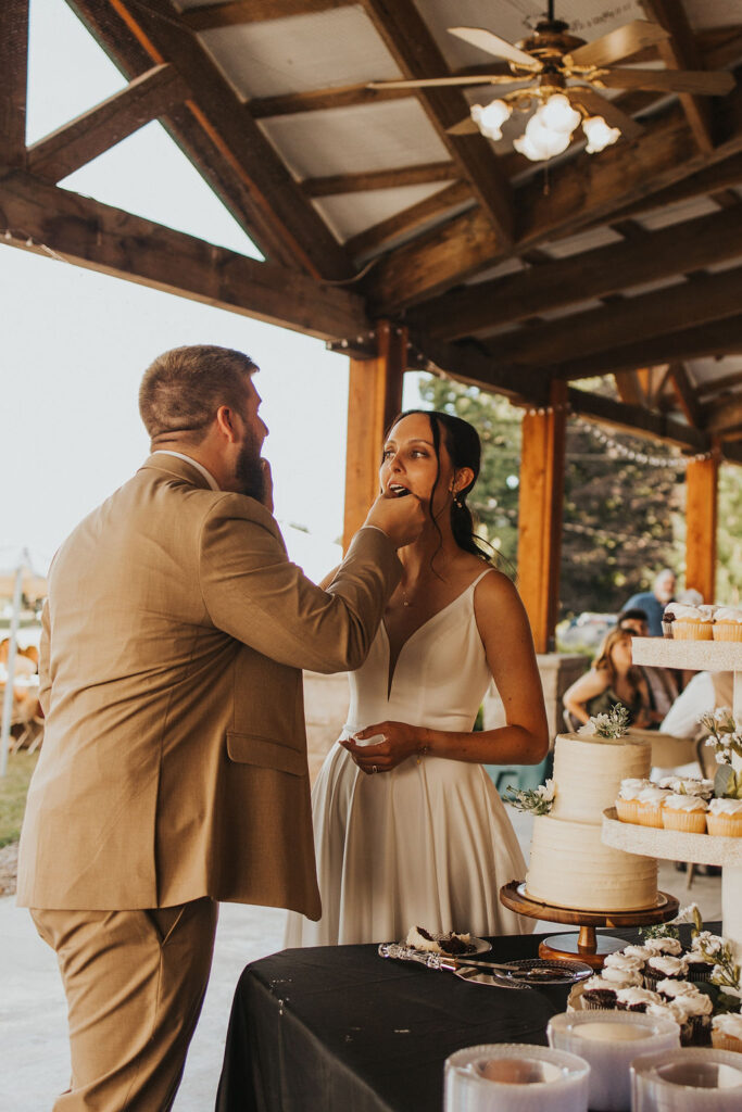 couple eats wedding cake together at backyard wedding reception 