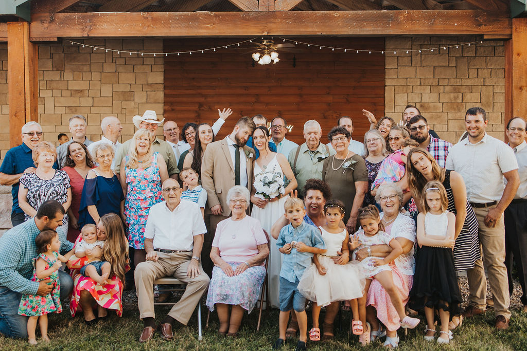 couple poses with guests at backyard wedding reception 