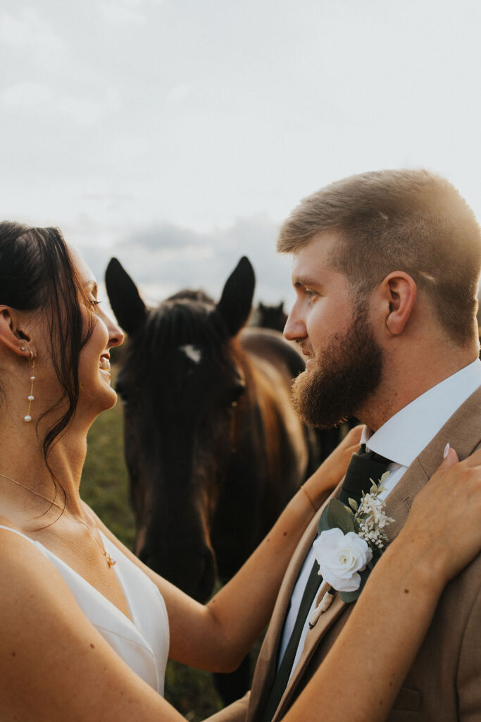 couple embraces in field with horses