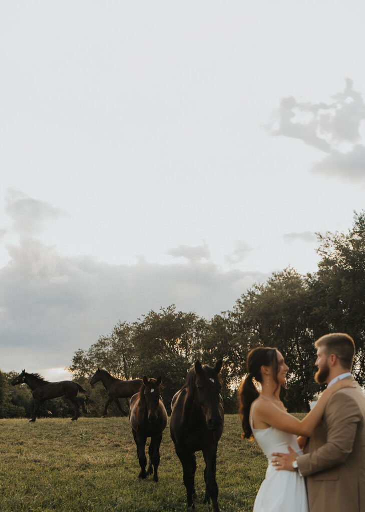 couple poses with horses in background