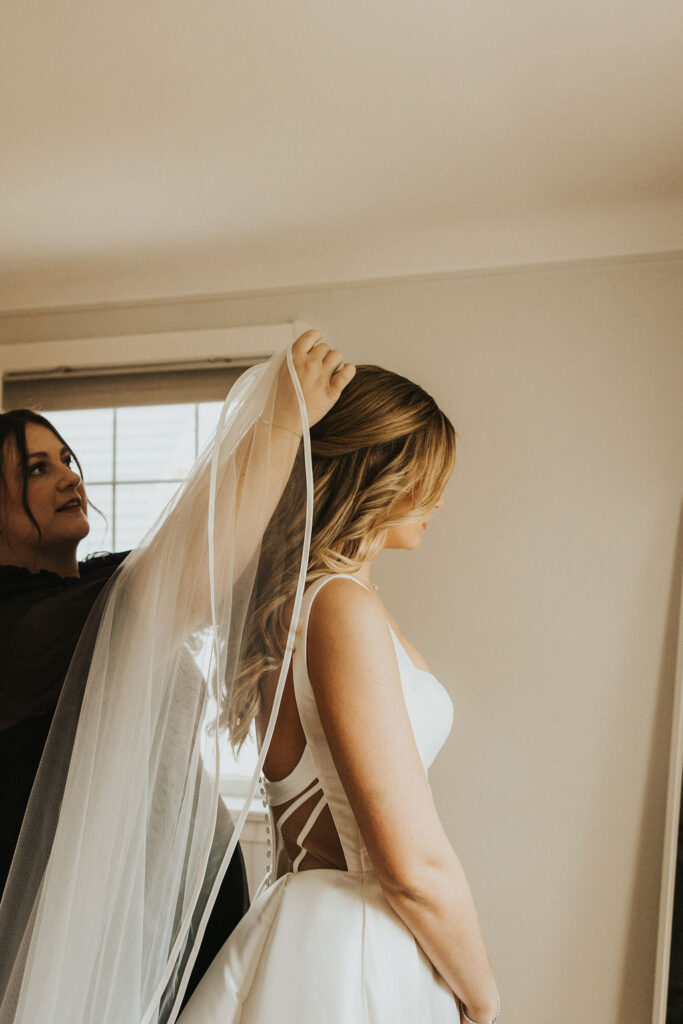 bride puts on veil during wedding getting ready