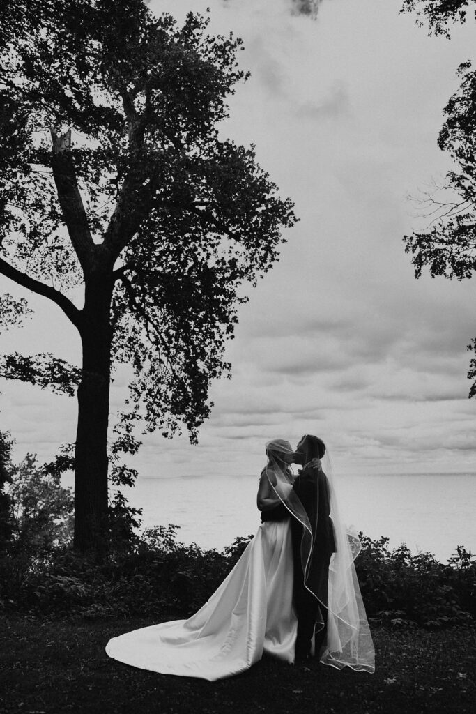 couple kisses under veil at lakeside wedding portraits