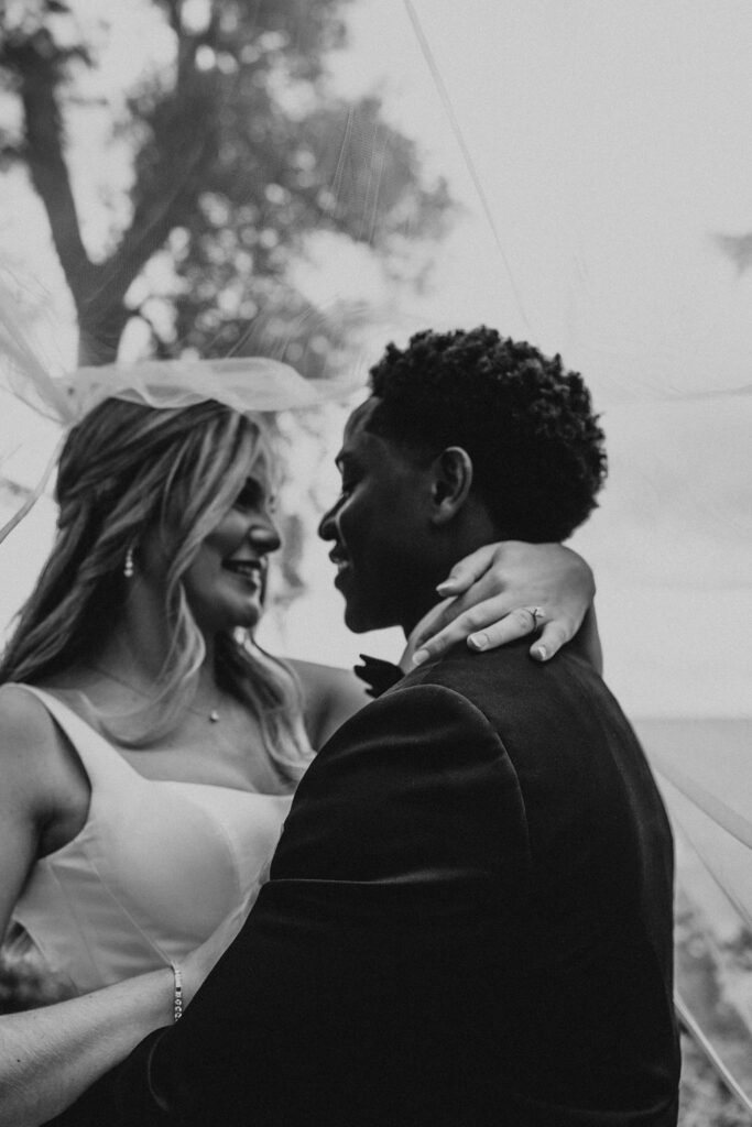 couple embraces under veil at lakeside wedding portraits