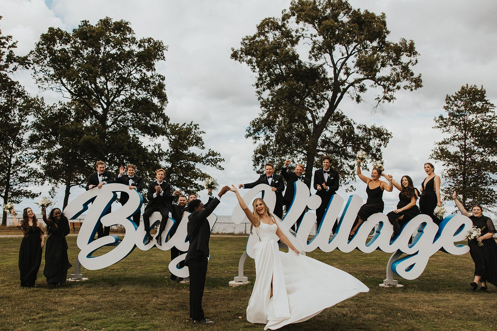 couple poses with wedding party at Bay Village waterfront