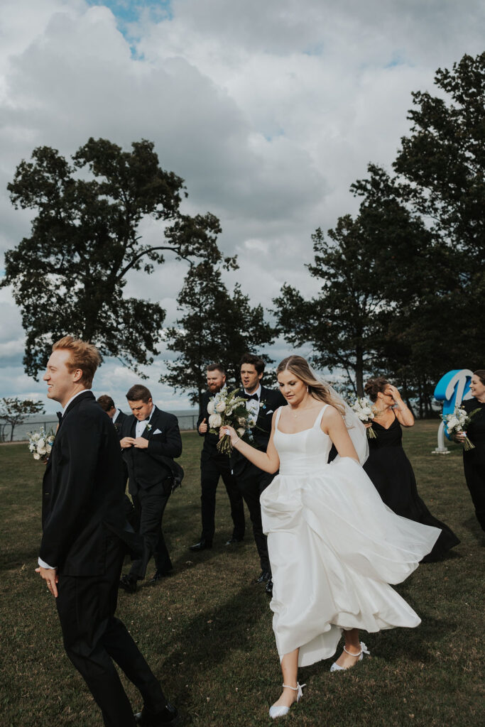 couple walks outdoors with wedding party 