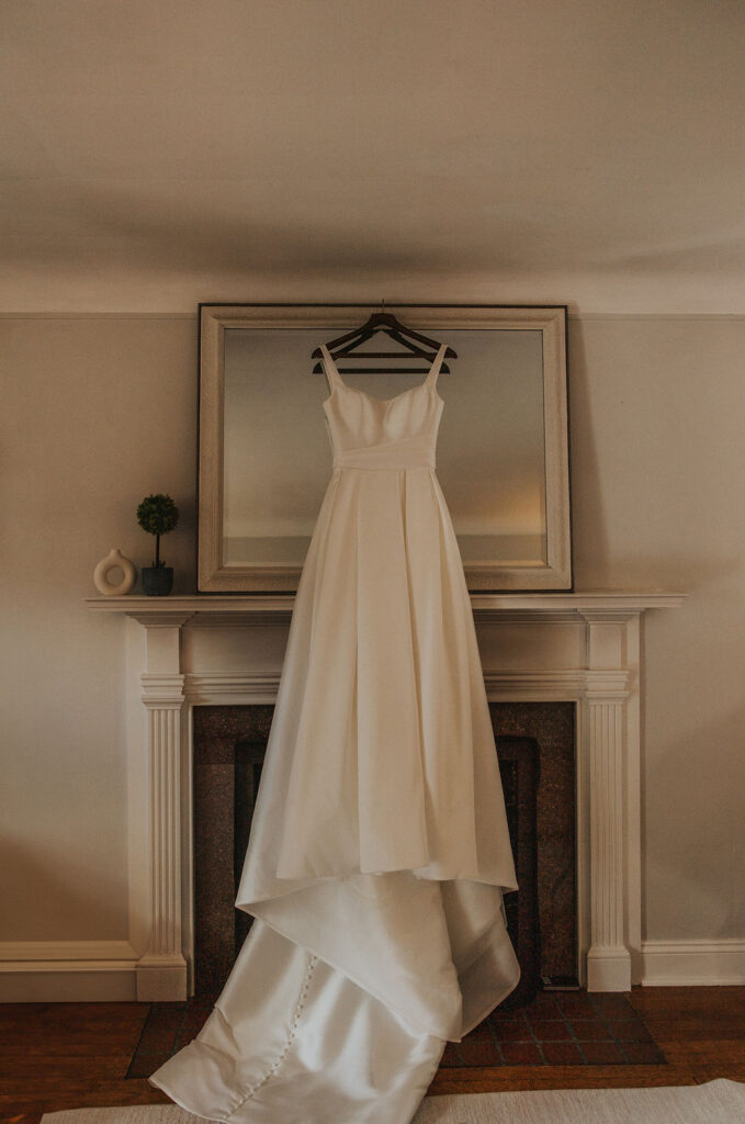 white wedding dress hangs above fireplace