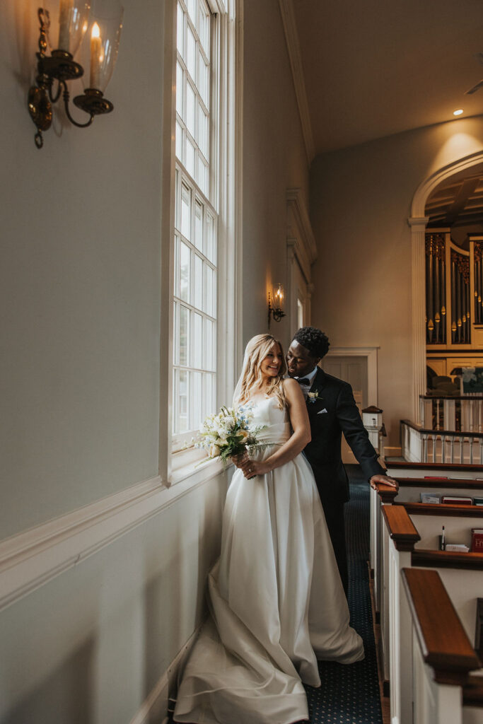 couple embraces beside church window