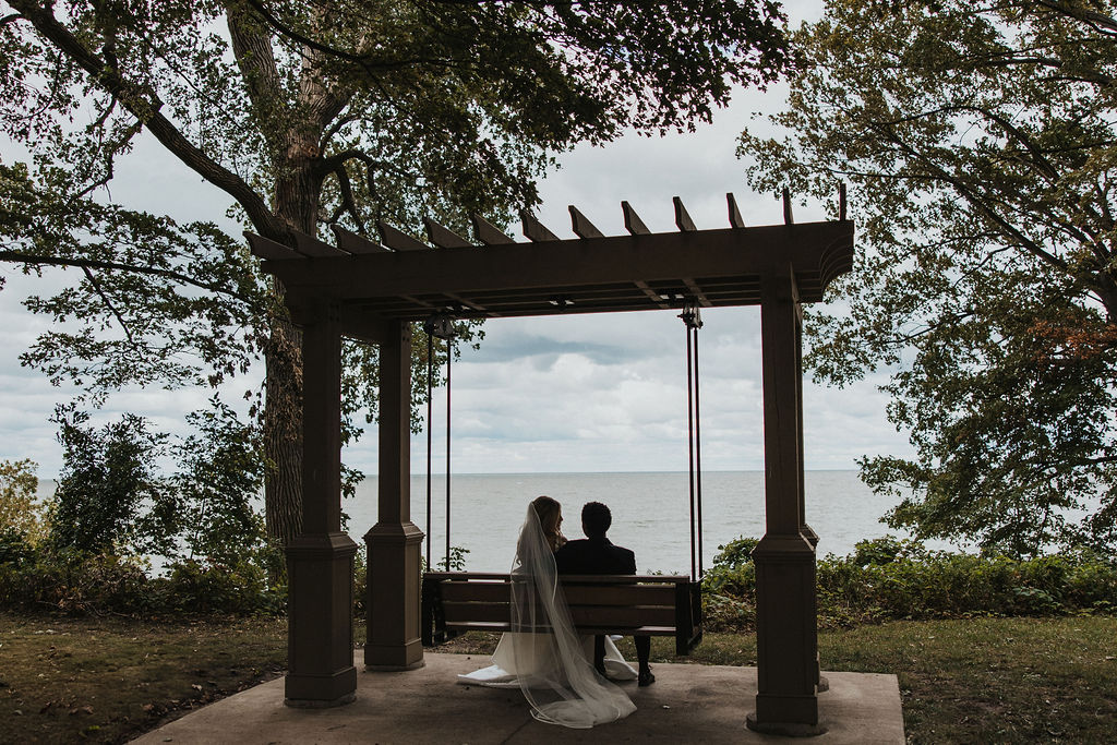 couple sits on swing during lakeside outdoor portraits