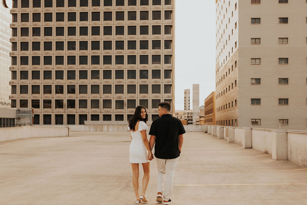 couple walk together holding hands on rooftop
