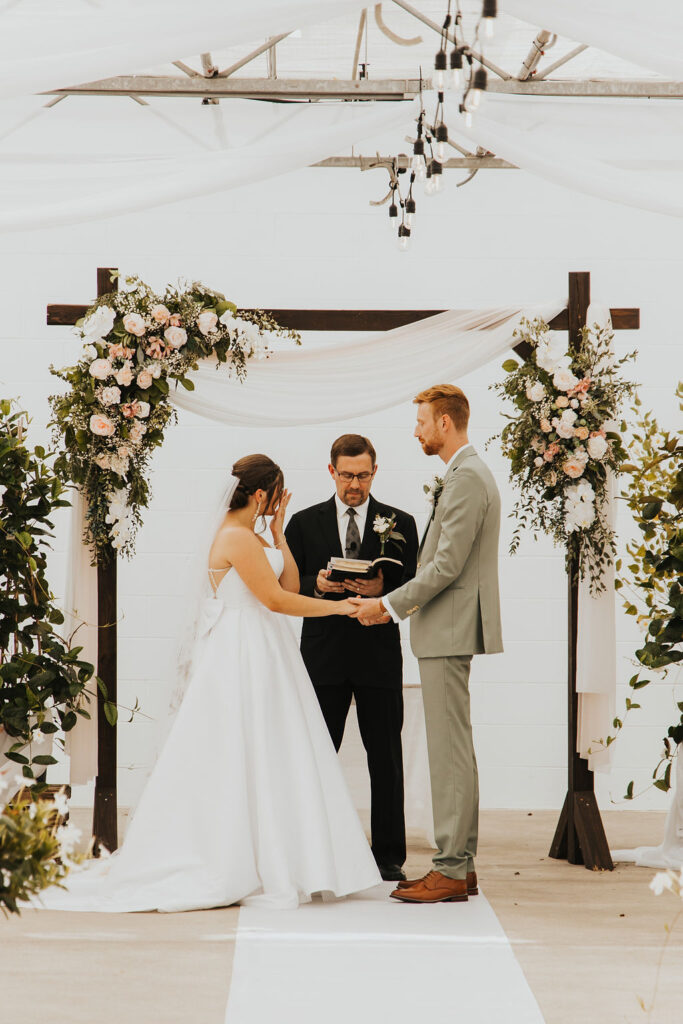 couple holds hands during Ohio greenhouse wedding ceremony