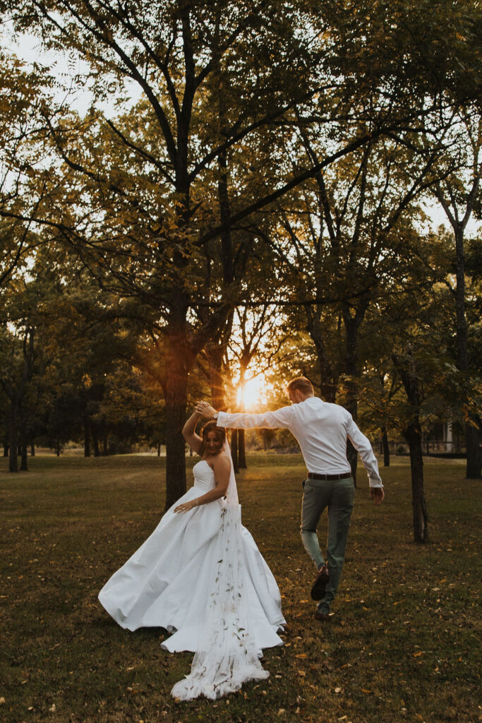 couple twirl together among the trees at sunset