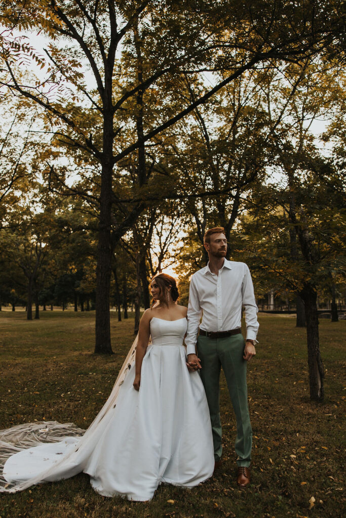 couple pose together among the trees at sunset