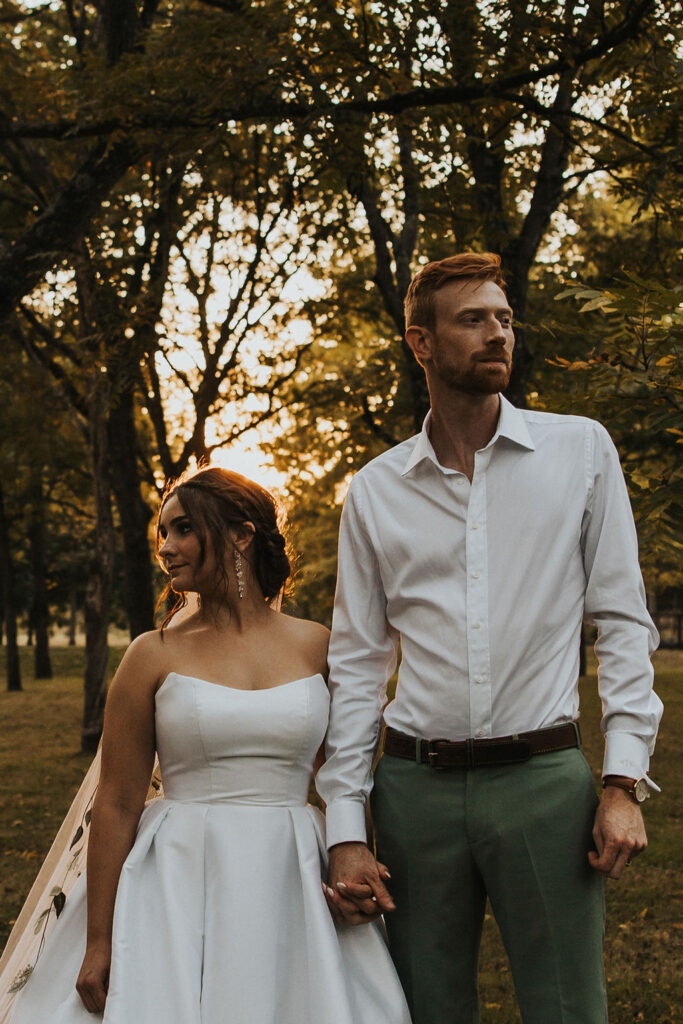 couple pose together among the trees at sunset