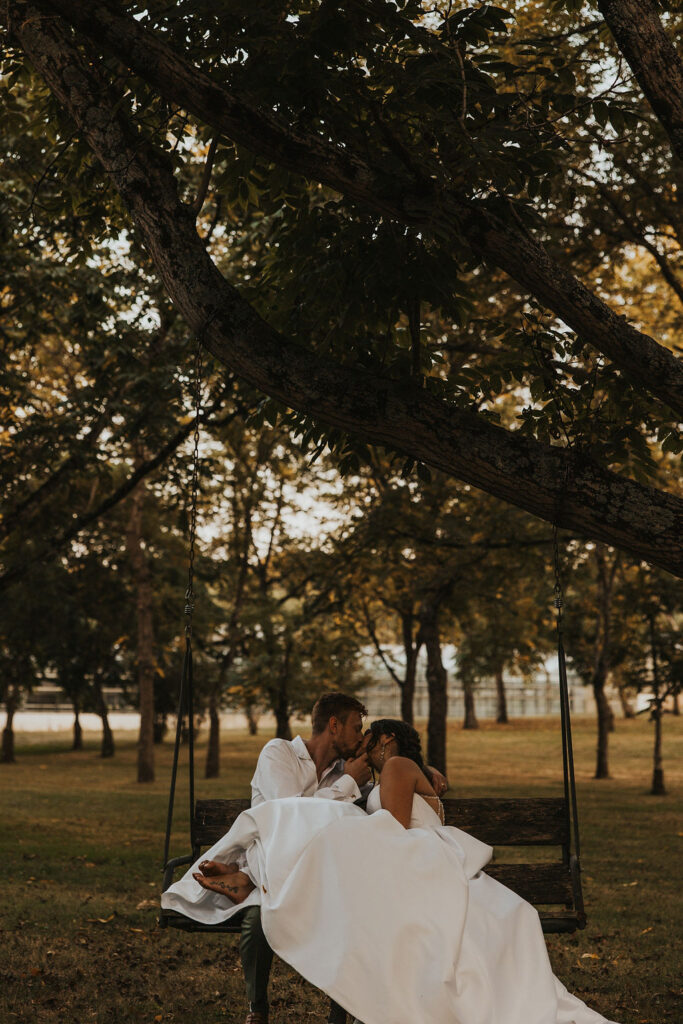 couple kiss while sitting on swing