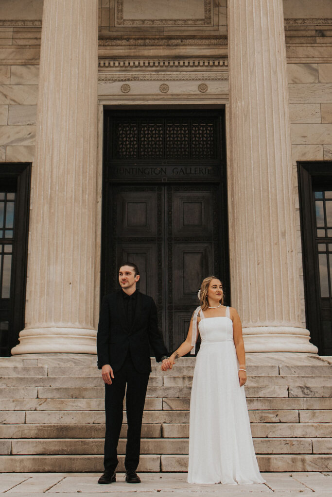 couple holding hands and standing in between pillars